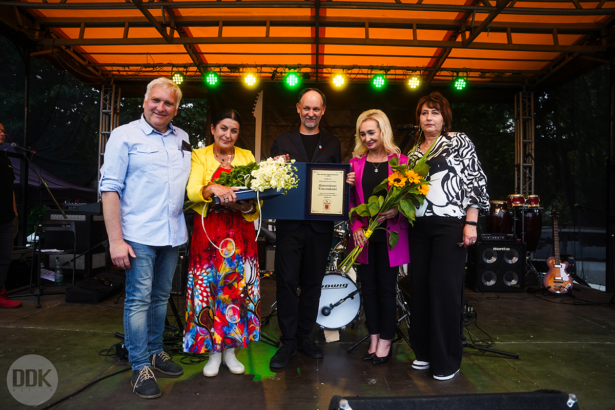 Zdjęcie grupowe; dwóch mężczyzn i trzy kobiety stoją na scenie; dwójka z nich prezentuje do obiektywu nagrody.